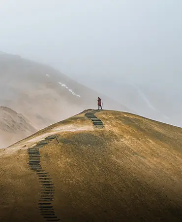 A hiker on a ridge trail in the mist